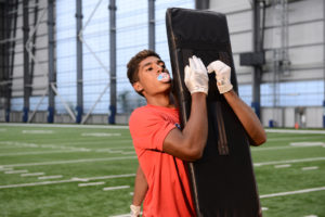 High School football player working on form tackle with a Tackle Dummy.
